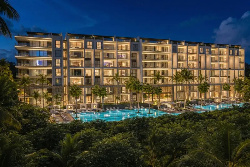 Desarrollo en preventa en Playa del Carmen de noche, con alberca iluminada
